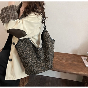 Detail of leopard print tote bag with black trim styled with a chic beige blazer outfit