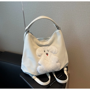 Close-up of cream white tote bag featuring a plush poodle patch and silver hardware