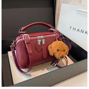 Détail du sac polochon en cuir bordeaux avec peluche dans un coffret cadeau