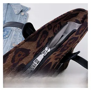 Macro shot of smooth silver metal zipper and leopard print fabric on a tote bag