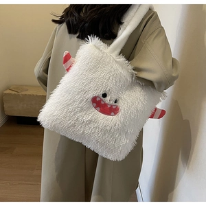 Détail du sac cabas monstre en peluche blanche avec broderie, porté sur un manteau
