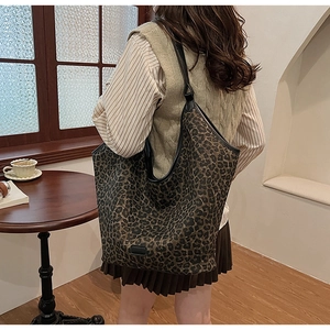Leopard print tote bag styled on model in a cozy vintage cafe setting with warm lighting