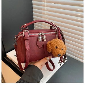 Détail du sac polochon bordeaux avec fermetures éclair argentées et breloque chien peluche