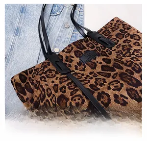 Close-up of leopard print tote bag with black leather handle on denim jacket