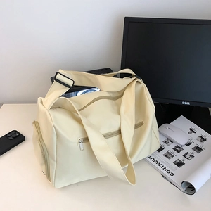 Macro detail of the spacious beige nylon gym bag with side shoe compartment on a desk