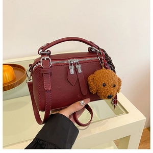 Gros plan du sac oreiller bordeaux avec double fermeture éclair et pendentif chien
