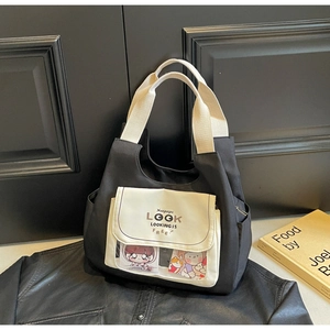 Close-up of black canvas tote bag featuring a clear display pocket and contrast handle