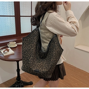 Detail of leopard print tote bag with black shoulder strap and decorative bottom patch