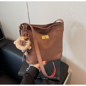 Detail of vintage brown suede shoulder bag with gold clasp and plush lamb pendant