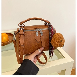 Gros plan du sac oreiller marron vintage avec pendentif ours et cuir texturé