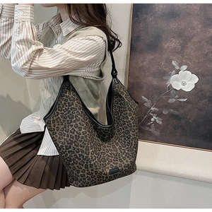 Close-up of a large leopard print hobo bag with black leather trim and vintage canvas texture