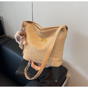 Detail view of khaki suede bucket bag featuring a gold clasp and cute bear charm
