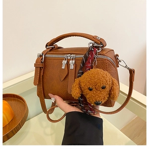 Détail du sac polochon en similicuir marron avec zips et breloque en peluche