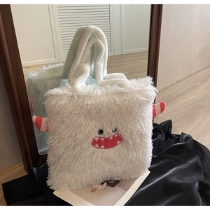 Détail du sac cabas en peluche blanche avec broderie de monstre rouge et grands yeux