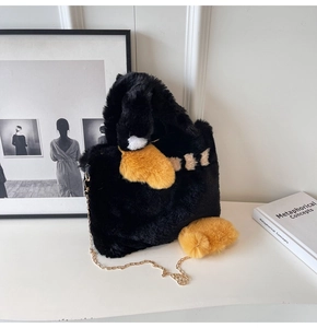 Gros plan d'un sac bandoulière en peluche noire avec chaîne dorée et détails jaunes fins