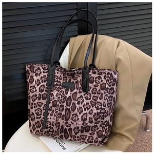 Detail view of large leopard print tote bag with black leather straps and logo patch