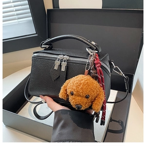 Détail du sac polochon vintage noir avec double zip et petit pendentif caniche