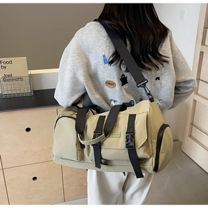 Détail du sac de voyage vert olive montrant les poches zippées et boucles fonctionnelles