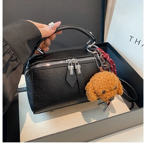 Détail d'un sac oreiller en cuir noir avec zip argenté et breloque ours en peluche
