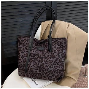 Detail of gray leopard print tote bag with black logo tag and leather strap