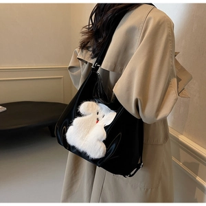 Close-up of a black glossy shoulder bag with a cute white plush puppy pattern on the front