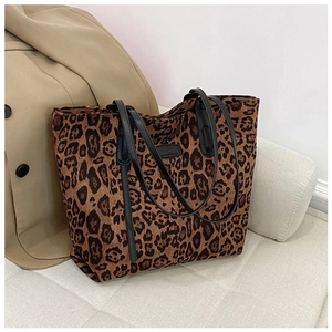 Detail of leopard print tote bag with black handles styled on a cozy cream sofa