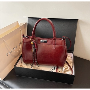 Détail du sac cabas bordeaux avec fermoir argenté présenté dans son coffret cadeau