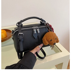 Vue détaillée du sac à main noir grainé avec fermetures éclair et pendentif ours