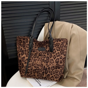 Detail shot of large leopard print tote bag on a white table with suit background