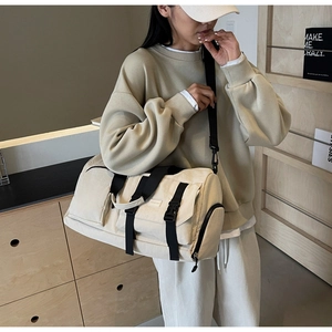 Détail du sac de voyage en toile avec sangle à boucle noire et poche latérale zippée