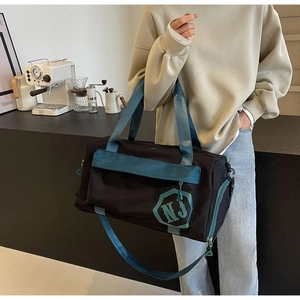 Détail du sac de voyage avec séparation sec-humide et logo NJ dans un décor de café