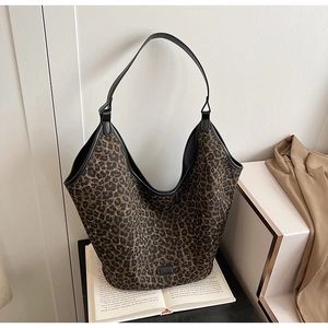 Detail of large leopard print hobo bag with black leather trim resting on a book