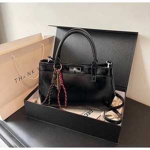 Sac à main noir brillant dans un coffret cadeau élégant avec un sac en papier blanc