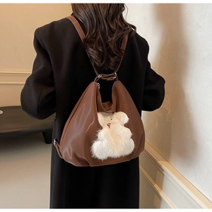 Brown tote bag with cute white plush bear patch shown on model in a modern room