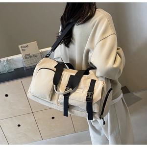 Détail du grand sac de voyage beige avec sangles noires et boucles latérales