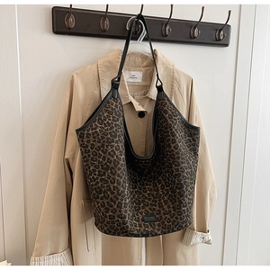 Large leopard print tote bag hung next to a khaki trench coat for a stylish autumn look