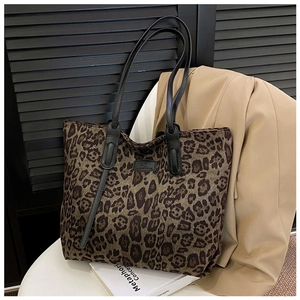 Detail of leopard print tote bag featuring black leather handles and oval logo patch