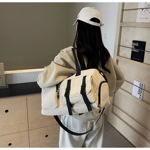 Détail d'un sac de sport en toile beige avec sangles noires et boucles de fermeture
