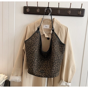 Detail of large leopard print tote bag with black trim hanging on a wooden hook