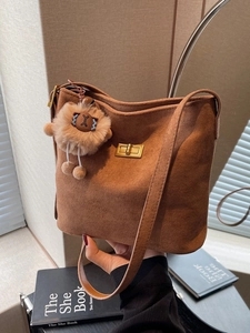 Caramel suede bucket bag with gold metal clasp and plush lion charm for women