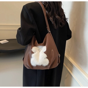 Detailed side view of the brown PU leather tote bag with a cute white plush bear patch