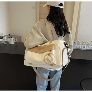 Détail du sac de voyage avec compartiment humide et sec, logo NJ et bandoulière