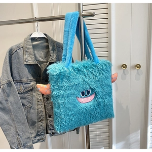 Gros plan du sac cabas en peluche monstre bleu avec broderie et petites cornes orange