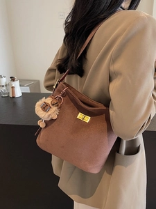 Brown faux suede bucket bag with gold buckle and lion plush charm on model