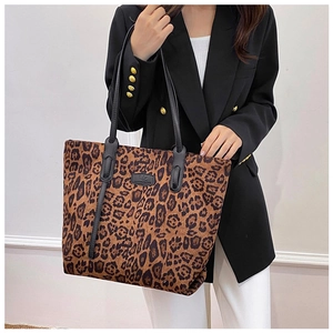 Detailed look at leopard print tote bag with black leather straps on a fashion model