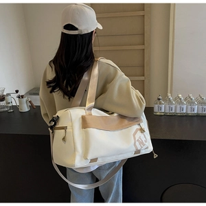 Détail du sac de fitness blanc cassé avec bordure kaki et logo NJ porté par un mannequin