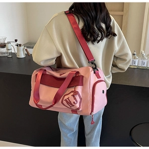 Vue détaillée du sac de fitness rose et rouge avec bandoulière et logo NJ brodé