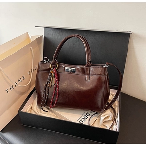 Vue détaillée d'un sac à main en cuir chocolat dans un coffret avec pendentif tissé