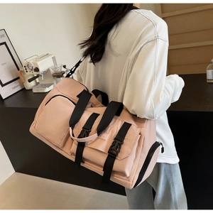Détail du sac de sport rose clair porté par un mannequin dans un café avec sangles noires