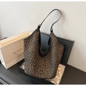 Detailed view of leopard print tote bag with black leather handle in luxury gift box